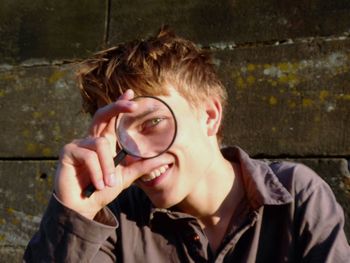 Portrait of smiling young man holding magnifying glass