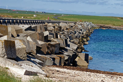 Stone wall by sea against sky