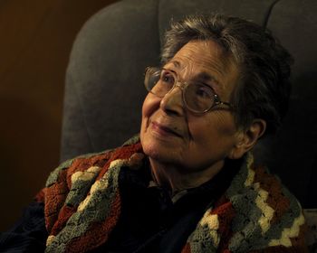 Close-up of senior woman sitting on seat at home