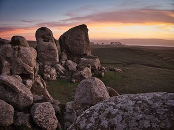 Rocks on land against sky during sunset