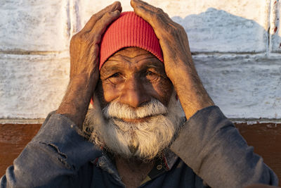 Portrait of an old indian man, old aged man with wrinkles on his face holding his face 