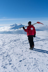 Rear view of person on snowcapped mountain against sky