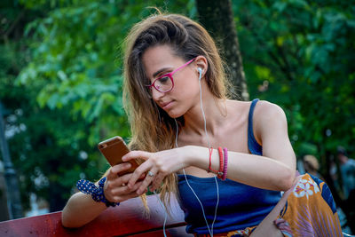 Young woman using mobile phone while sitting in public park