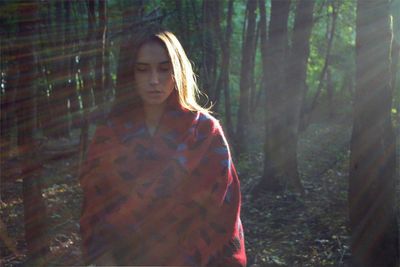 Young woman amidst trees in forest