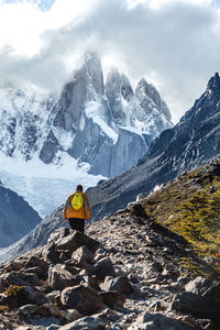 Scenic view of snowcapped mountains against sky with a man climbing up