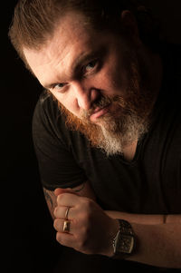 Close-up portrait of mid adult man against black background