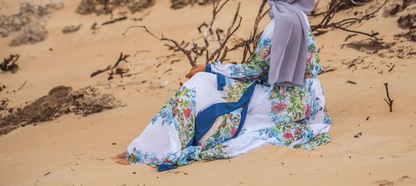 Muslim lady in a scarf relaxing on sand at beach.