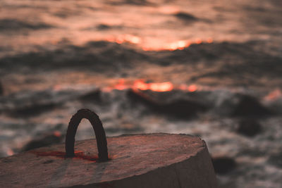 Close-up of rusty metal on rock against sky during sunset