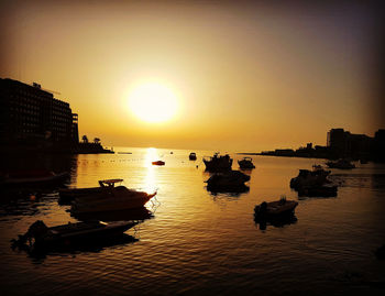 Silhouette boats in sea against sunset sky