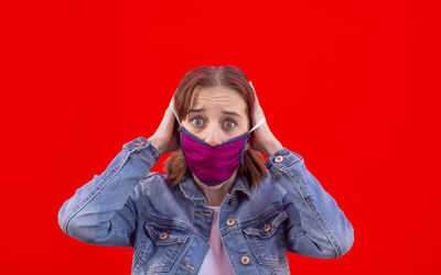 Portrait of young woman standing against red background