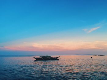 Boats in sea at sunset