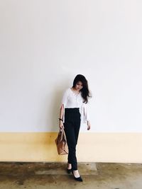 Young woman standing against wall