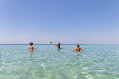 Happy teenagers playing volleyball in water at the vacation and fun