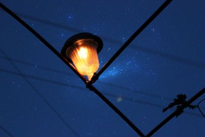 Low angle view of illuminated lamp against sky at night