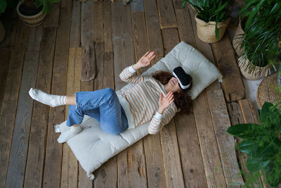 Shocked by vr young woman in virtual reality glasses watching 360 degree video lying on wooden floor