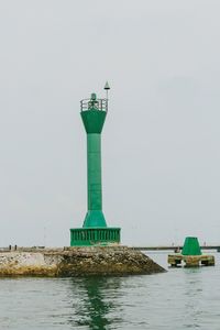 Lighthouse amidst sea against clear sky