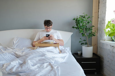 Portrait of young woman sitting on bed at home
