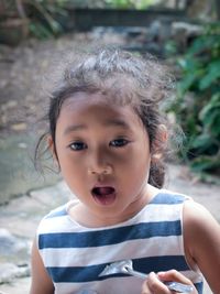 Close-up of girl with mouth open holding spoon while standing outdoors