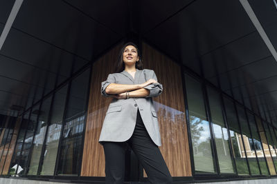 Businesswoman with arms crossed standing outside office building