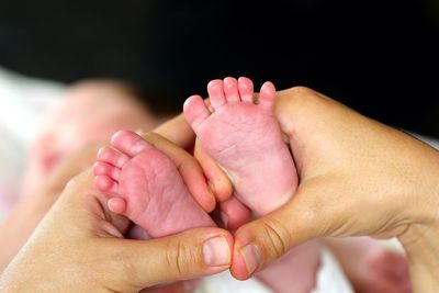 Cropped image of mother holding baby feet