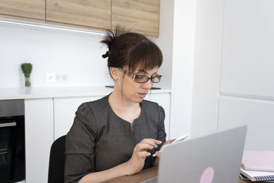 Side view of businesswoman using laptop at home