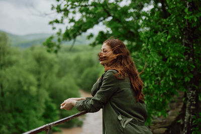 Side view of woman standing against trees