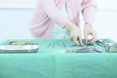 Midsection of female doctor arranging medical instrument on table