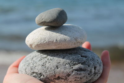 Close-up of hand holding stones at beach