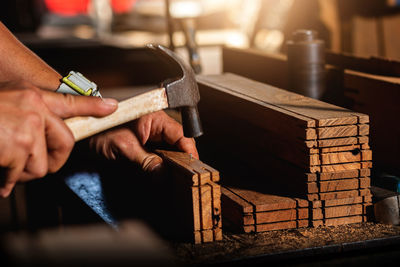 Close-up of a carpenter using a circular saw or a tool to cut wooden planks to make furniture  