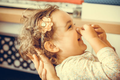 Happy little girl pinching her nose and having fun with mother at home.