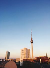 Communications tower in city against clear blue sky