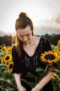 Beautiful young woman with yellow flower in field