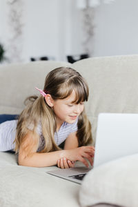 Girl using computer lying on sofa