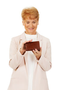 Woman holding smart phone while standing against white background