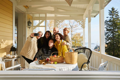 Happy mature friends posing for cell phone selfie on porch