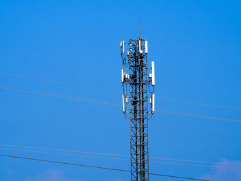 Low angle view of electricity pylon against clear blue sky