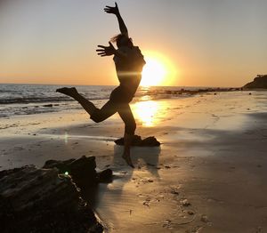 Silhouette person on beach against sky during sunset