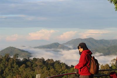 Side view of woman standing on observation point against sky