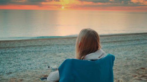 Rear view of woman looking at sea during sunset