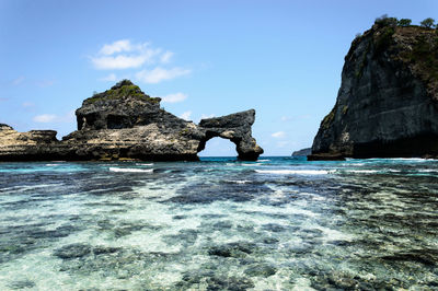 Rock formation in sea against sky