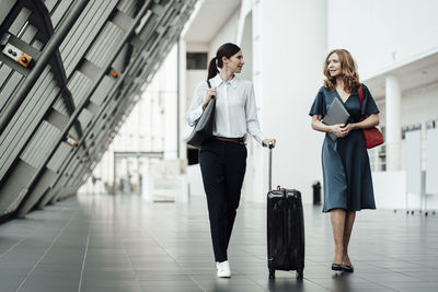 Female professionals discussing while walking in corridor at office