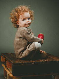 Portrait of cute girl sitting against gray background