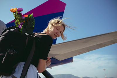 Low angle view of woman standing against blue sky