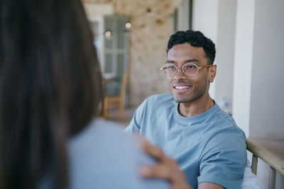 Smiling young man talking with woman sitting in patio