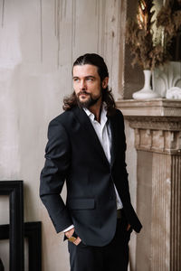 Portrait of young man standing against wall