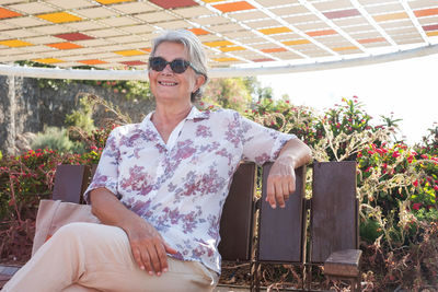 Smiling woman wearing sunglasses sitting on bench