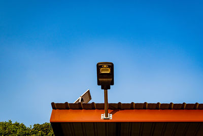 Low angle view of security camera against clear blue sky