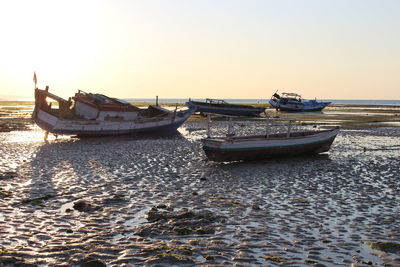 Boats moored on shore against clear sky