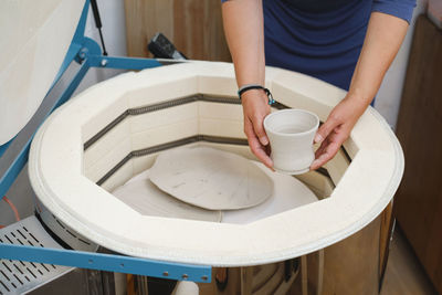 Close-up of hands putting vase into the kiln, oven for roasting of unbaked clay handmade products