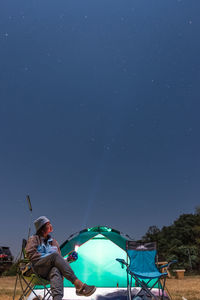 Man holding blue umbrella against sky at night